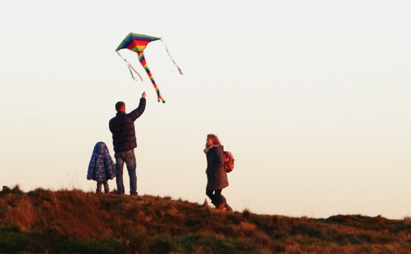A young family flying a small kite.